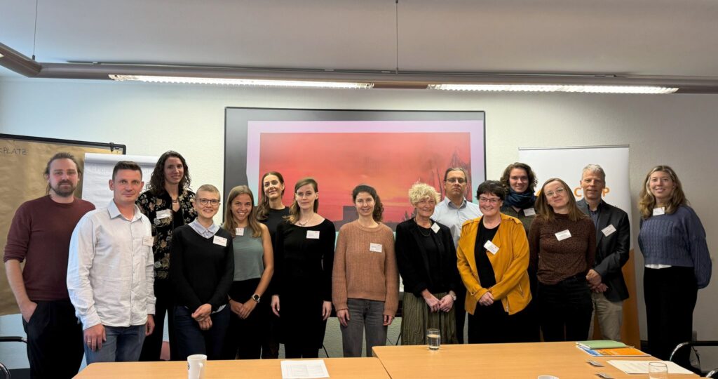 Auf dem Bild die 15 Teilnehmenden des Workshops in einer Reihe hinter einem Pult und vor dem Banner des CPHP